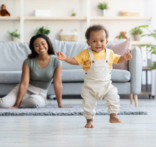 First Steps. Adorable Black Infant Child Walking In Living Room At Home